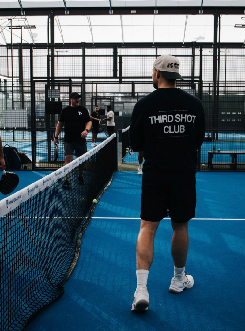 Person playing padel on a court with 'Third Shot Club' branding.