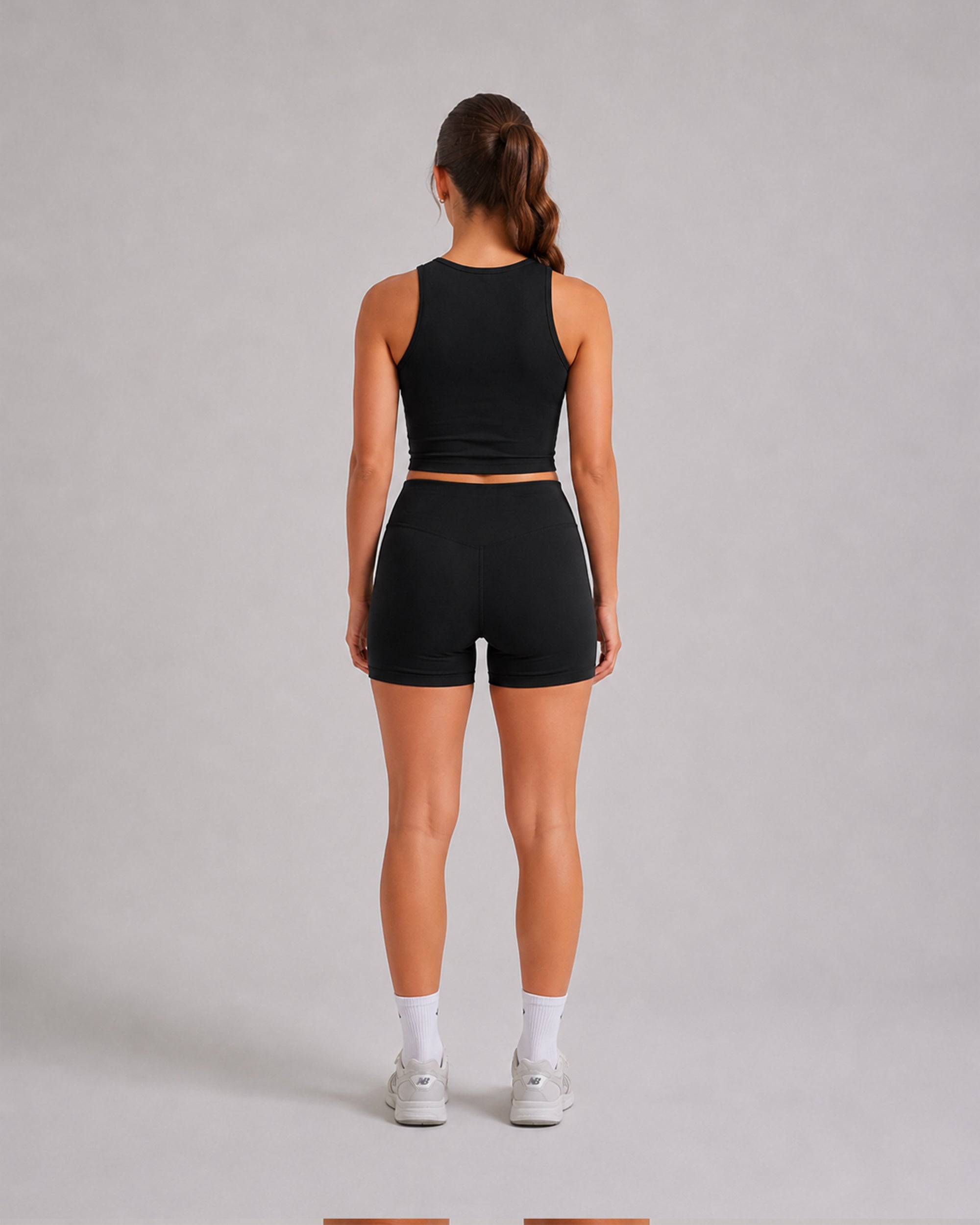 Model wearing the Women's Sports Crop Tank in black with matching bike shorts, back view