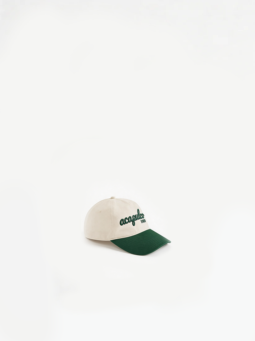 The Acapulco Cap in ecru and green — angled view showing two-tone brim